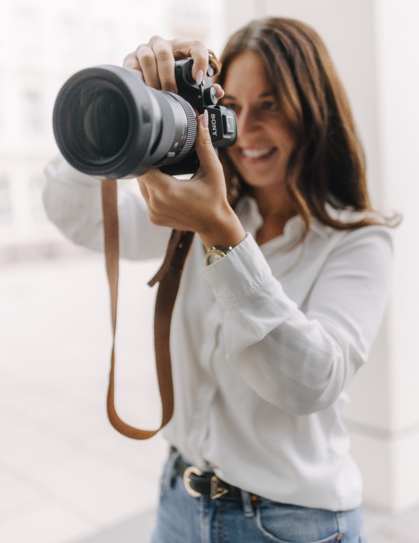Maria Wündisch, Fotografin in Magdeburg mit Kamera in der Hand, lächelt und zielt auf das Motiv.