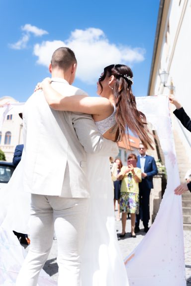 Braut und Bräutigam umarmen sich, während Gäste an einer Trauung teilnehmen.