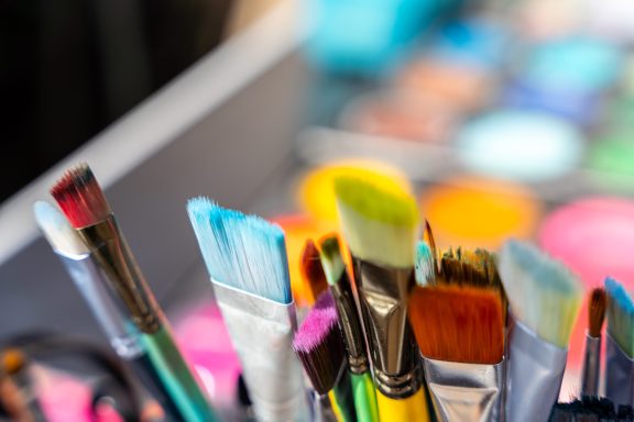 Bunte Pinsel und Farbpaletten in einem Make-up-Koffer.