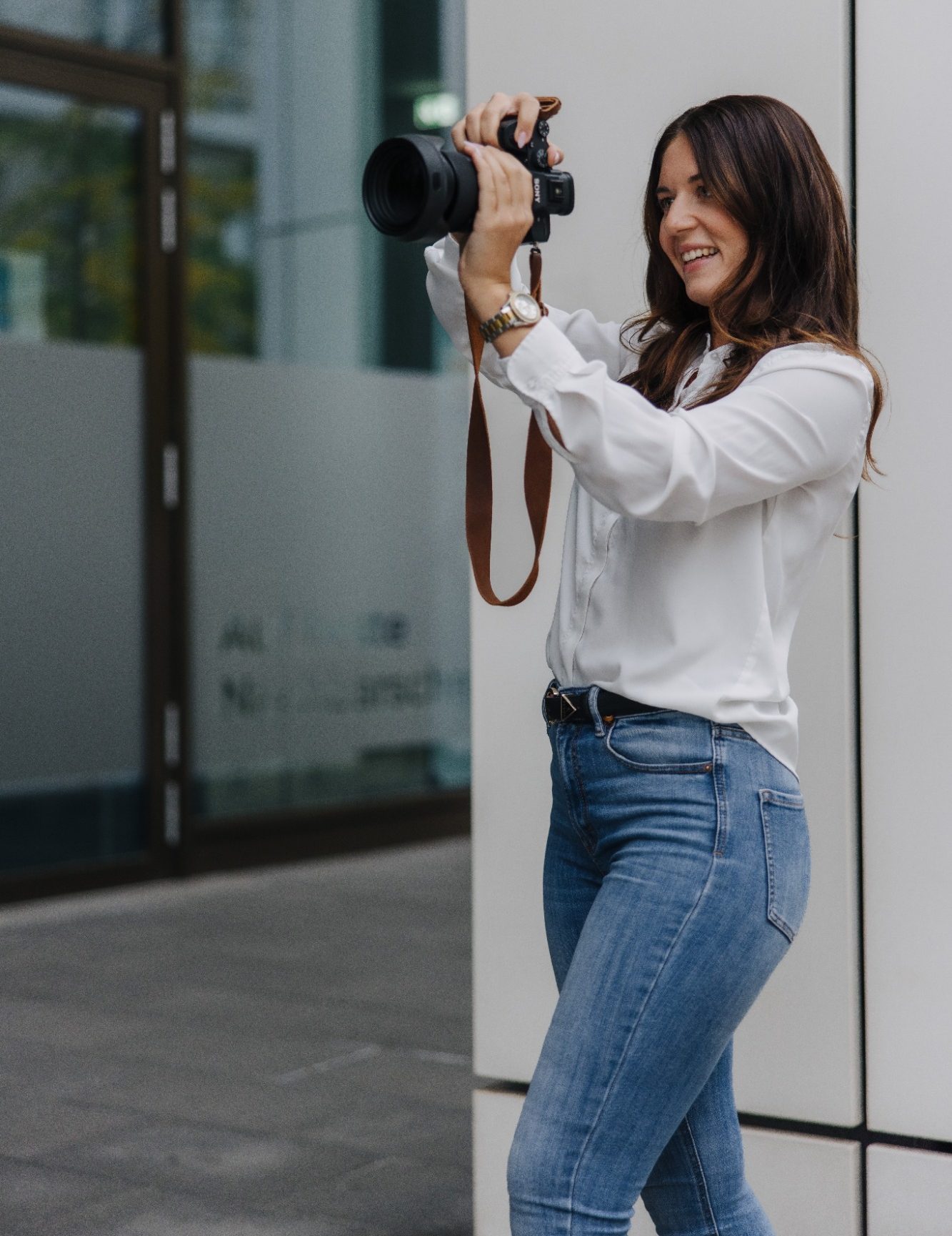 Maria Wündisch, Fotografin in Magdeburg mit Kamera in der Hand, lächelt und zielt auf das Motiv.