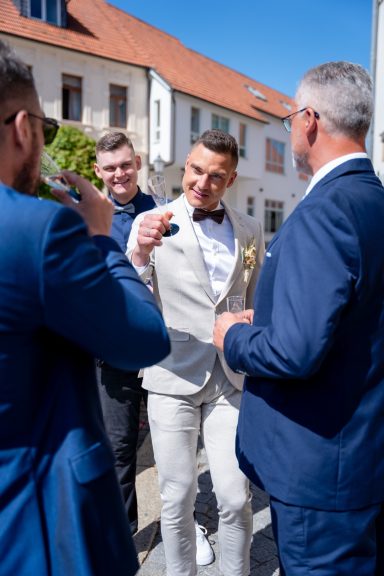 Ein festlich gekleideter Mann spricht mit anderen Herren im Freien.