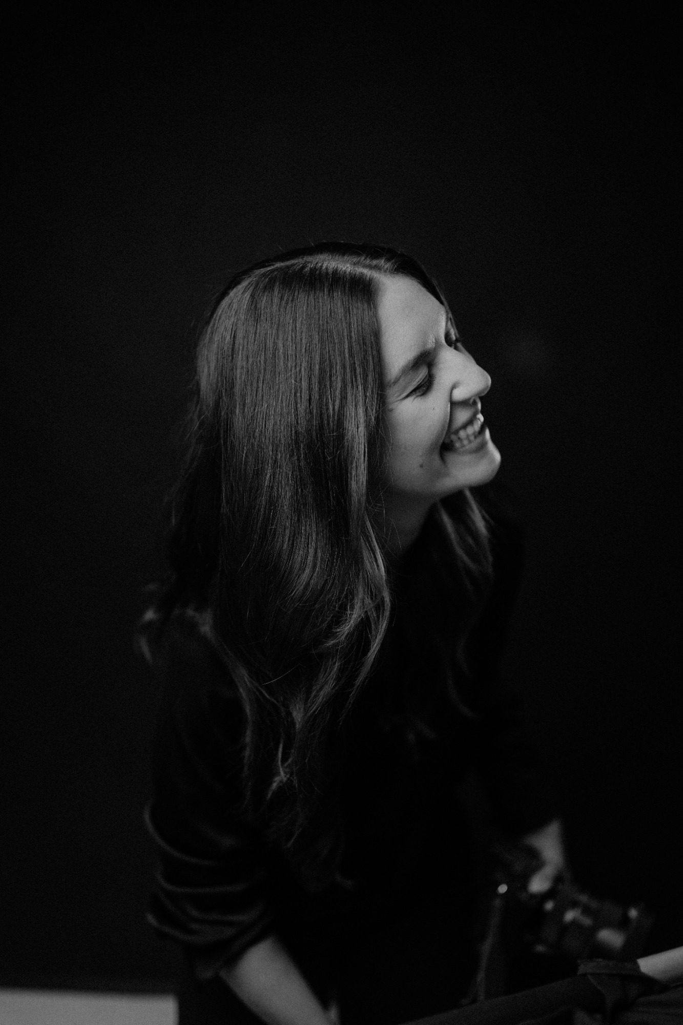 Lächelnde Frau mit langen Haaren, vor einem schwarzen Hintergrund.