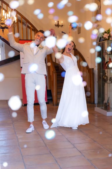 Brautpaar tanzt fröhlich auf der Feier, umgeben von schimmernden Konfetti.