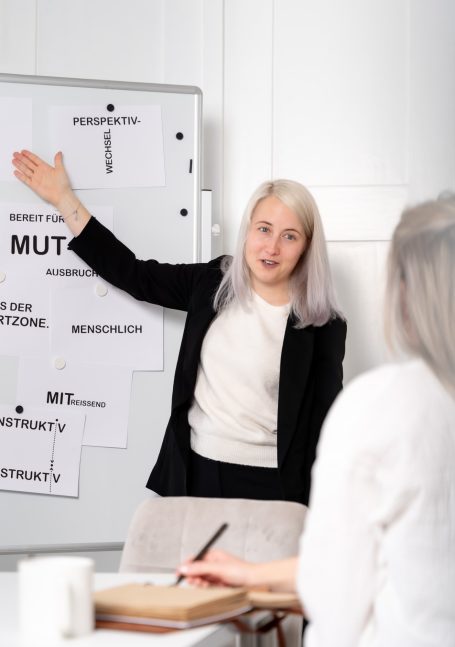 Frau präsentiert Informationen an einem Flipchart während einer Besprechung.