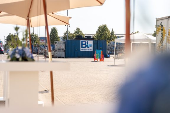 Blick auf einen blauen Container und einige Pflanzen in einem sonnigen Außenbereich.