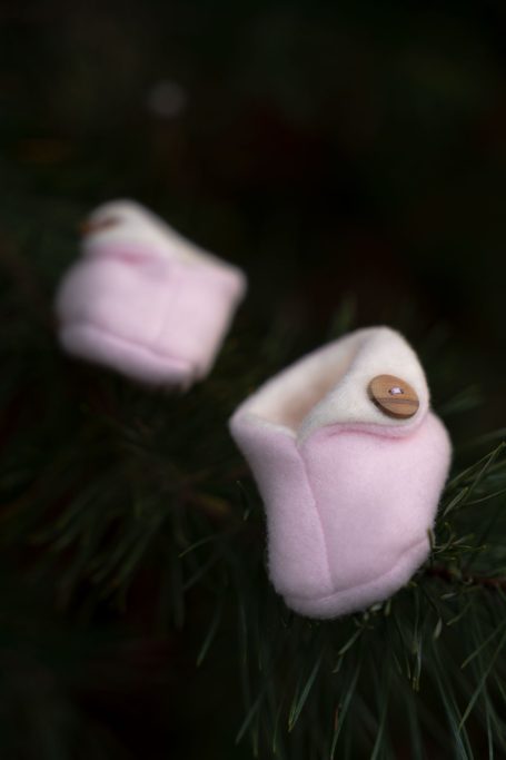 Zwei rosa Baby-Stiefel mit einer weißen Innenseite und einem Knopf.