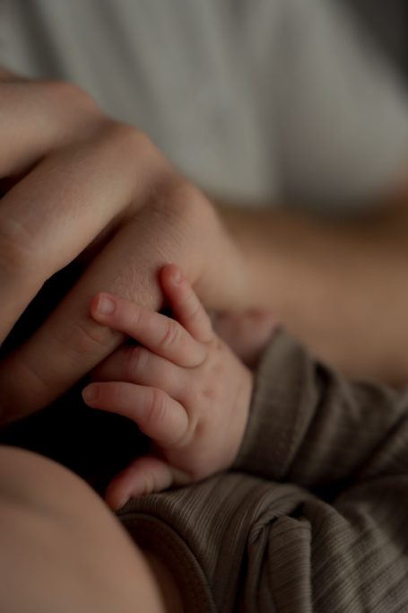 Ein kleiner Babyhand greift eine erwachsene Hand in sanfter Umarmung.