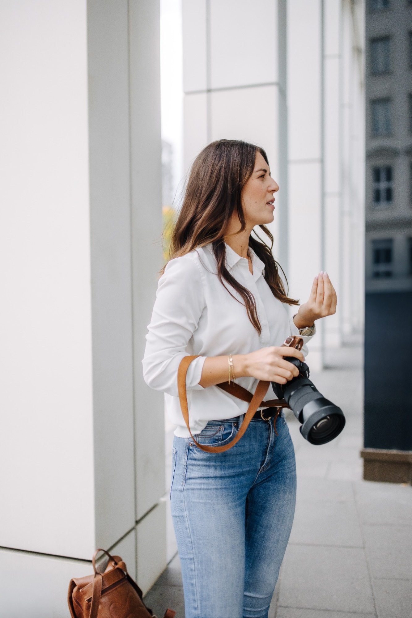Maria Wündisch mit Kamera in der Hand, steht an einem modernen Gebäude.