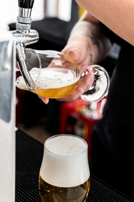Ein Bier wird frisch aus einem Zapfhahn in ein Glas eingeschenkt.