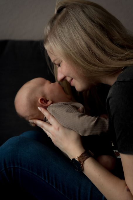 Eine lächelnde Frau hält ein Baby an der Nase, beide schauen sich liebevoll an.