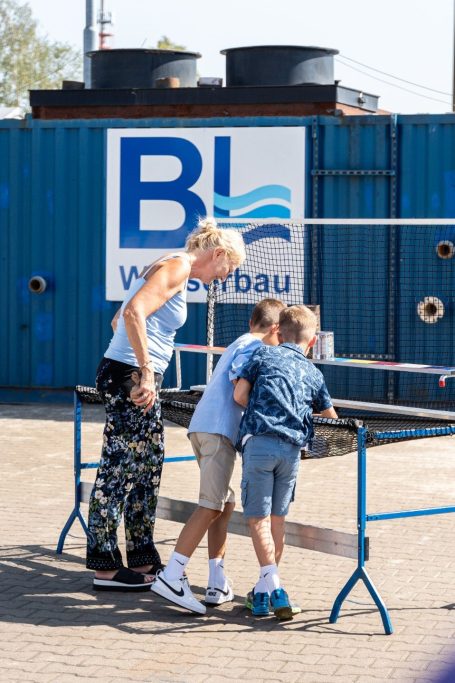 Drei Kinder und eine Frau stehen an einem Tisch, während sie etwas betrachten.