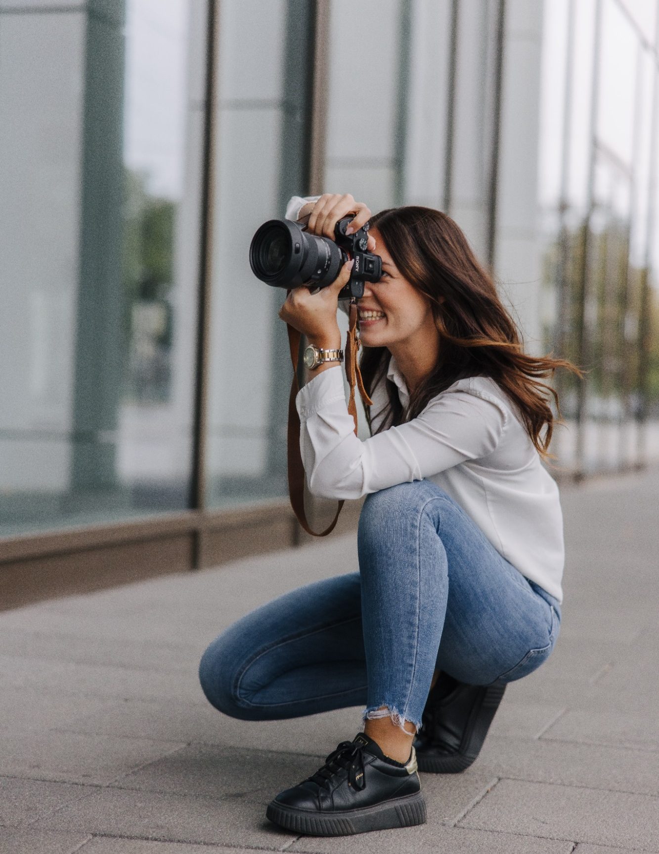 Maria Wündisch, Fotografin in Magdeburg mit Kamera in der Hand, lächelt und zielt auf das Motiv.